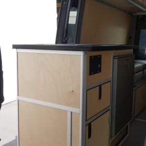 New Way Van Life Mercedes Sprinter interior galley countertop and stacked drawer storage detail with overhead cabinets and touchscreen control panel, New Way Van Life sign visible through open sliding door