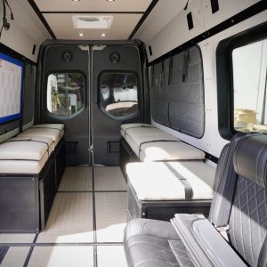 Custom cream automotive-grade vinyl seat cushions installed on driver and passenger side bed systems inside a Mercedes Sprinter van conversion by New Way Van Life