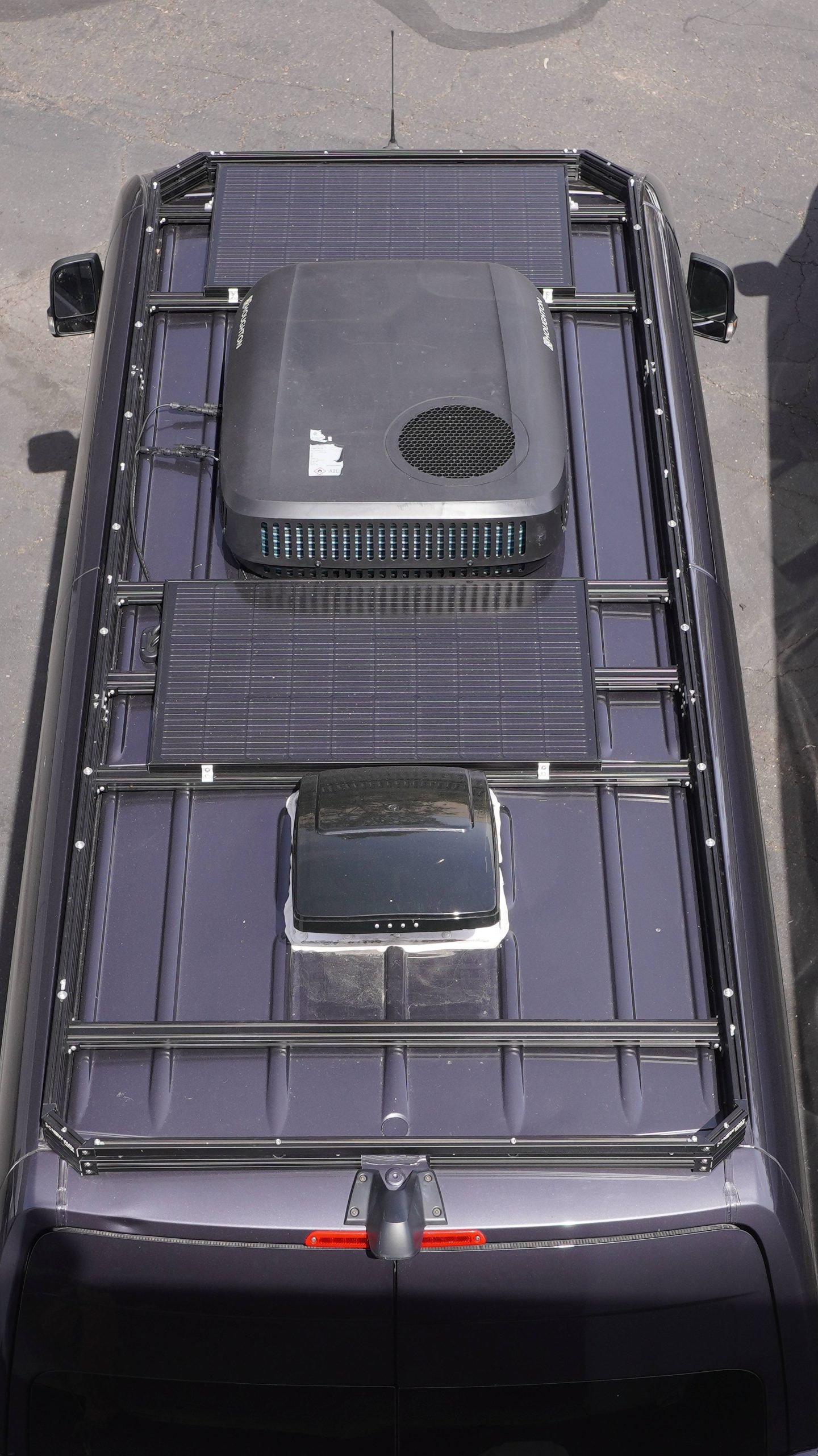 Aerial top-down view of Mercedes Sprinter van black roof rack fully loaded with solar panels Houghton rooftop AC unit and MaxxAir MaxxFan roof vent by New Way Van Life