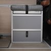 New Way Van Life Wrappon toilet cabinet with gray vinyl cushion top and retention strap closed inside a Mercedes Sprinter van conversion